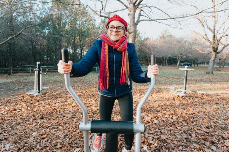 Old woman doing exercise training workout at the park on the machines